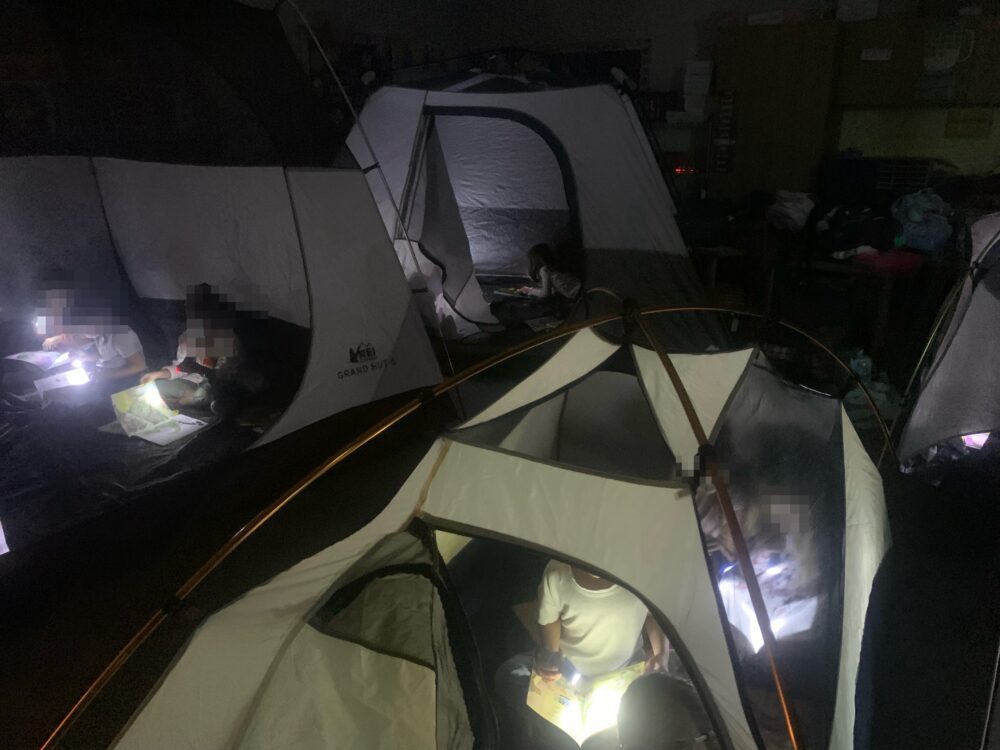 Students reading in tents with flashlights on Camping Day