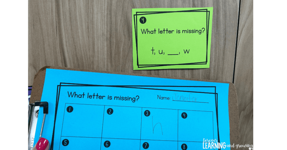 a write the room activity is shown with a green task card asking for the missing letter hung up on a door and a recording sheet in blue